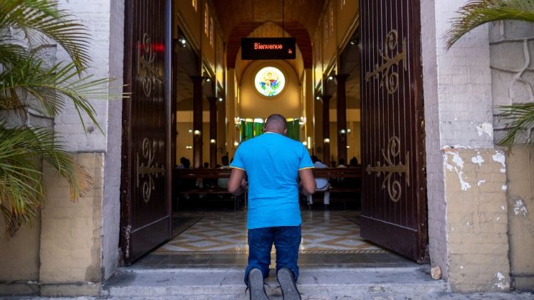 Un hombre ora a la entrada de una iglesia en Puerto Príncipe, Haití –  Diario Católico